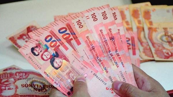Manos sosteniendo billetes de banco de Bolivia.
