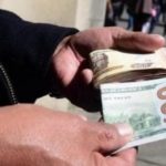 Persona sosteniendo un billete de 100 dólares y otros billetes.