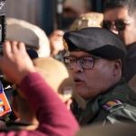 Un hombre con uniforme militar rodeado de personas y cámaras.