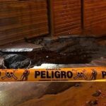 Imagen de una calle con un socavón y cinta amarilla de advertencia.