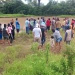 Grupo de personas reunidas al aire libre cerca de un estanque.