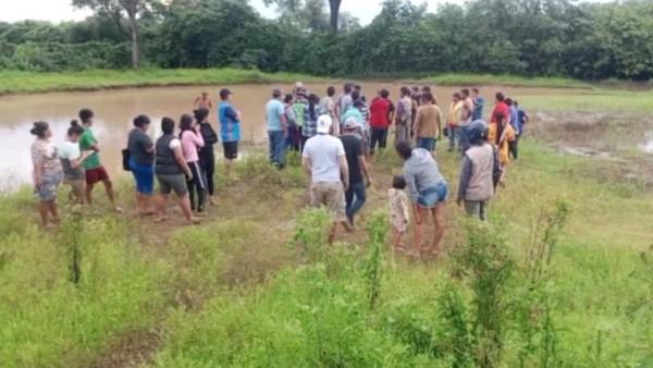 Grupo de personas reunidas al aire libre cerca de un estanque.