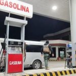 Una gasolinera con un vehículo y personas presentes.