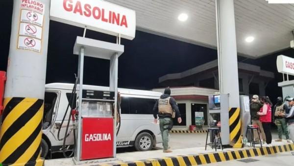 Una gasolinera con un vehículo y personas presentes.