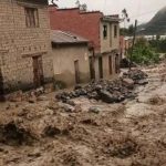 Calle inundada con corrientes de barro en un entorno urbano.