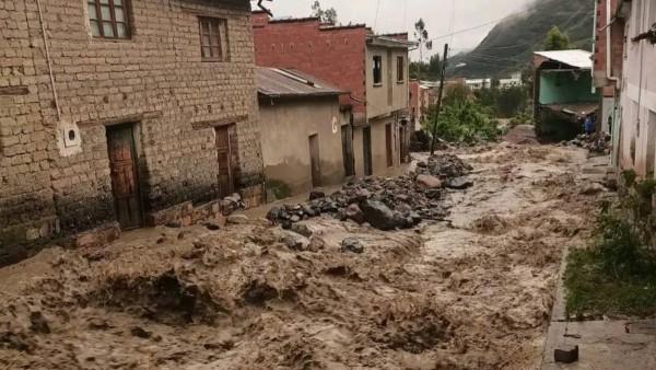 Calle inundada con corrientes de barro en un entorno urbano.