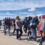 Grupo de personas caminando por una carretera bajo un cielo azul con nubes.