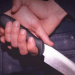 Manos sosteniendo un cuchillo grande con el filo hacia abajo.
