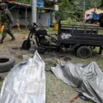 Soldado pasa junto al cuerpo de un hombre y su motocicleta carbonizada tras una explosión