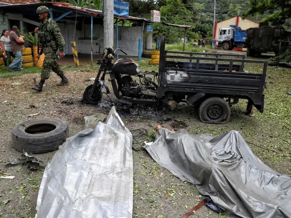 Soldado pasa junto al cuerpo de un hombre y su motocicleta carbonizada tras una explosión