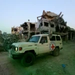 Un vehículo de la Cruz Roja junto a edificios dañados en Gaza.