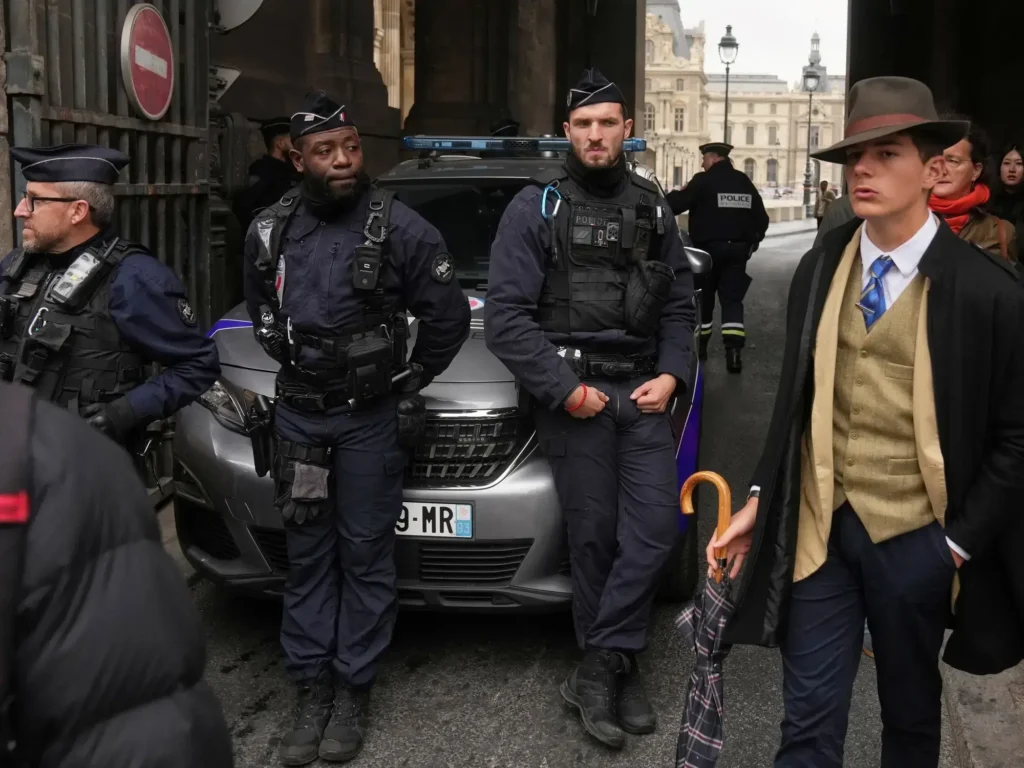 Pedro Elías Garzón Delvaux pasa junto a policías que bloquean una entrada al Louvre tras el robo.
