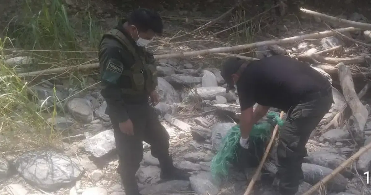 Dos policías realizan el levantamiento de los restos humanos.