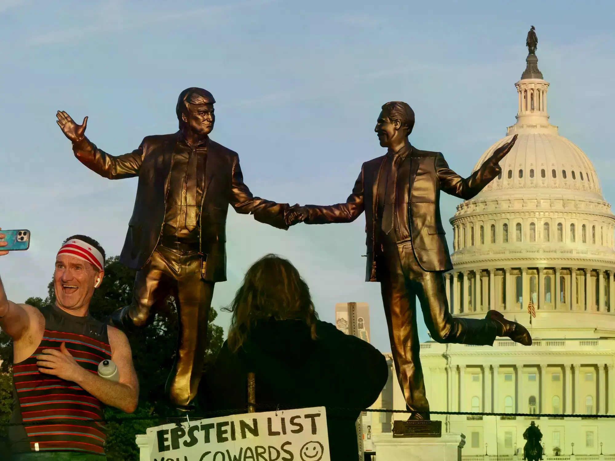 Una estatua que representa al presidente Donald Trump y a Jeffrey Epstein tomados de la mano se alza al atardecer en el Natio