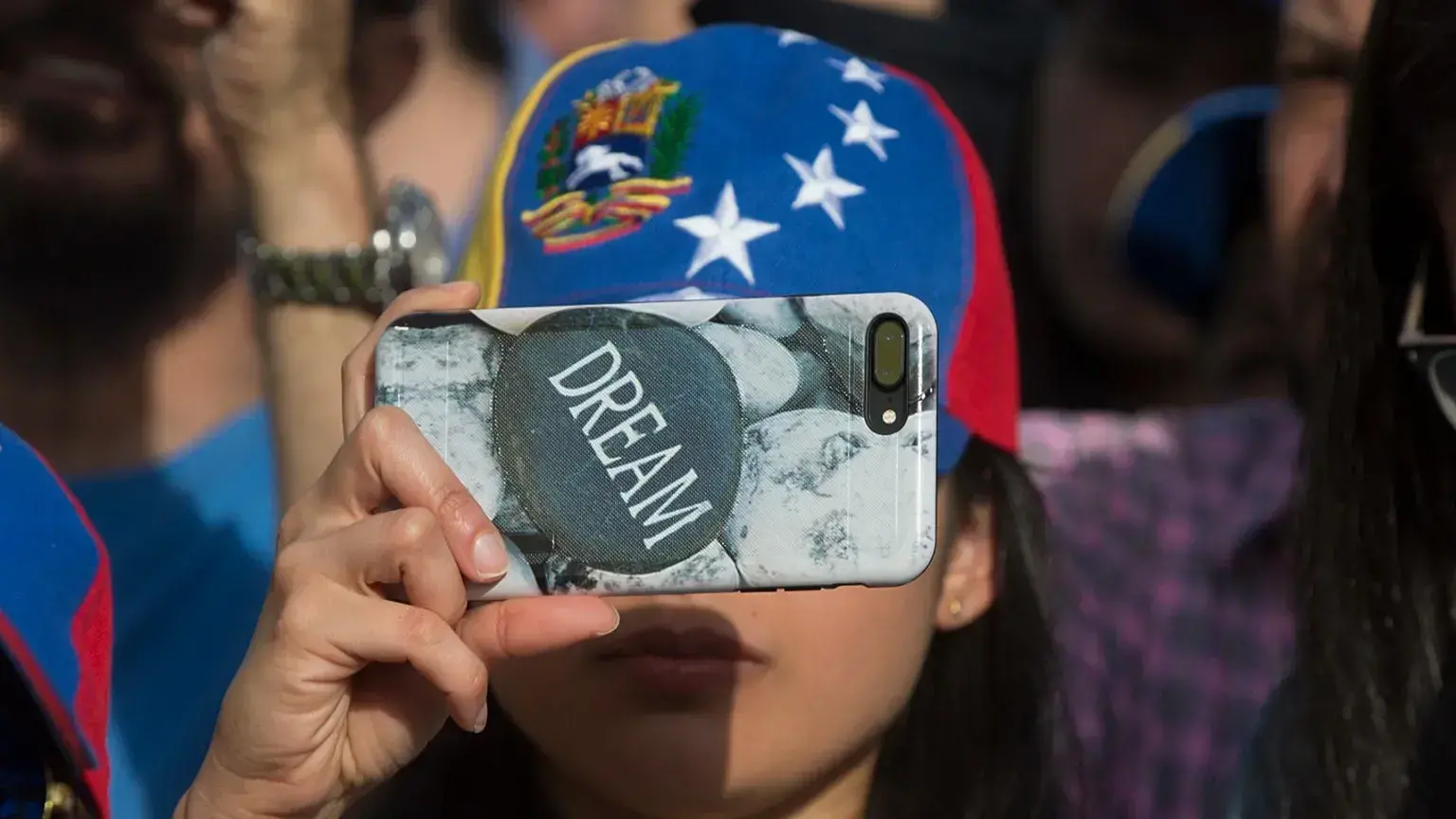 Una mujer toma fotos con un teléfono celular con una funda protectora con el mensaje 'sueño' durante una protesta en Madrid,