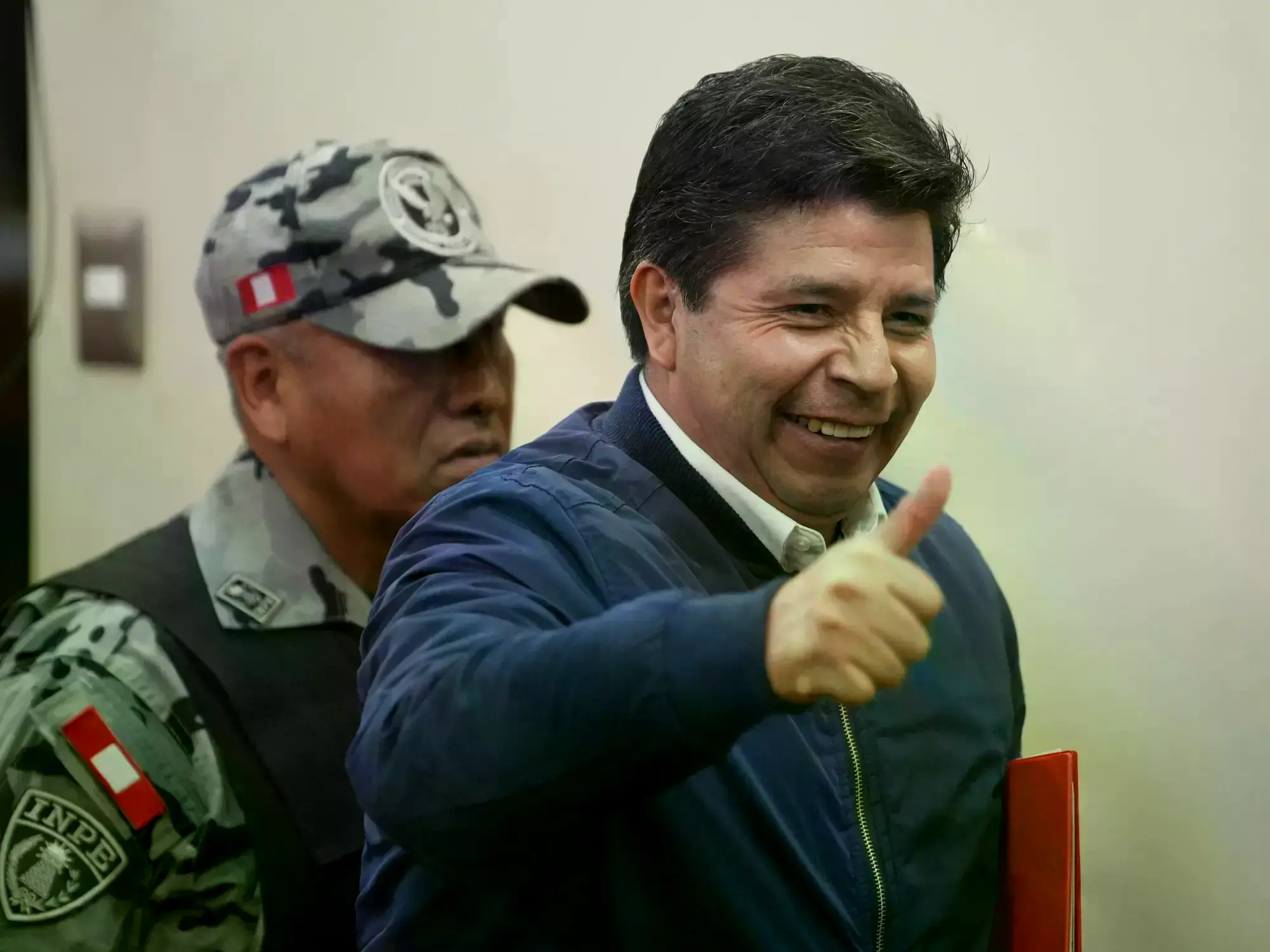 El ex presidente Pedro Castillo, acusado de rebelión, levanta el pulgar al llegar a una audiencia de sentencia.