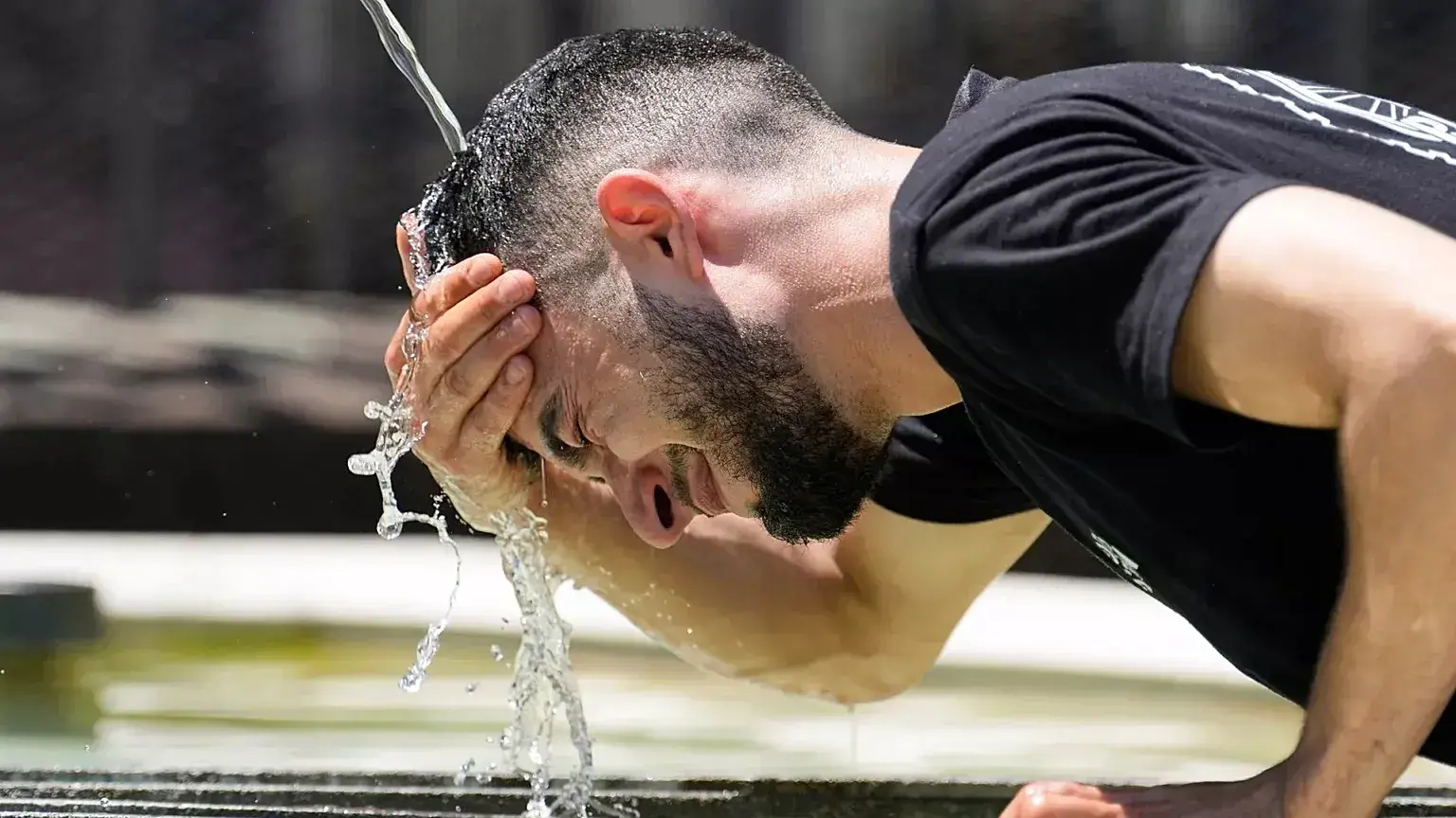 Un trabajador se refresca en una fuente durante una ola de calor en Basilea, Suiza