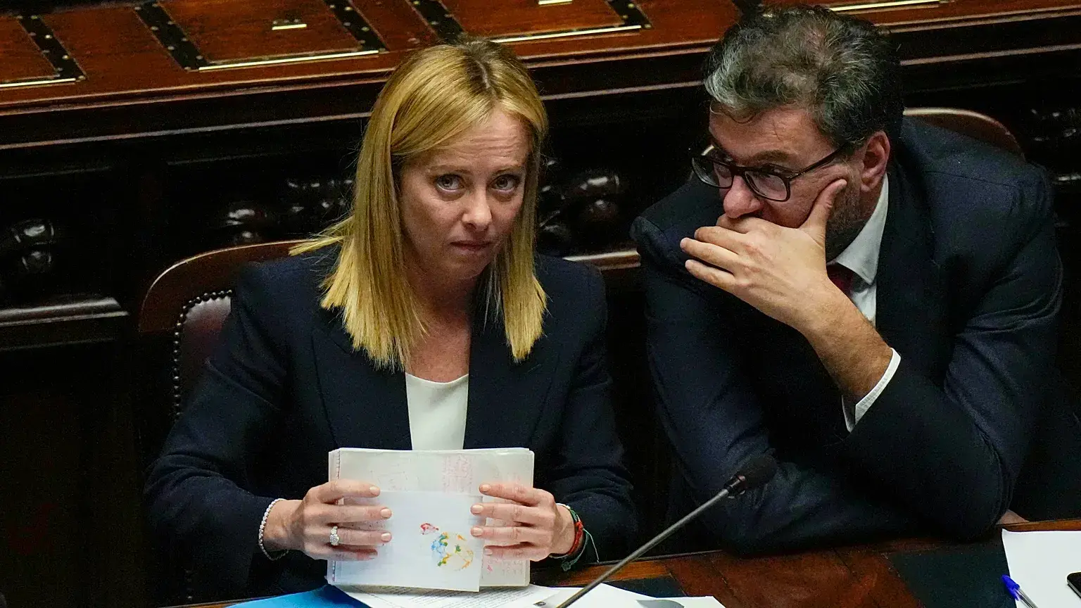 Giancarlo Giorgetti, ministro de Economía italiano, susurra junto a la primera ministra, Giorgia Meloni, en una imagen de arc