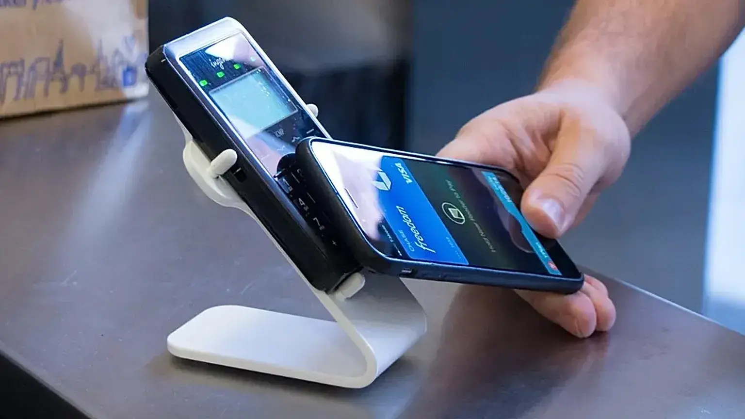 Persona realizando un pago con un teléfono móvil en una terminal.