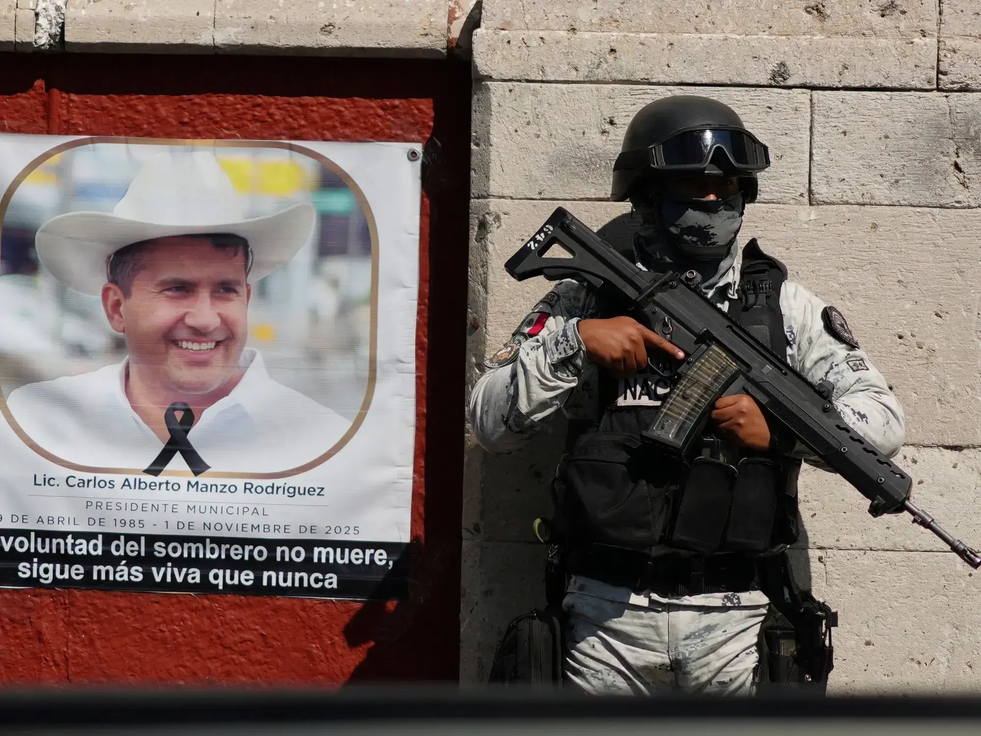 Un miembro de la Guardia Nacional junto a un retrato del alcalde Carlos Manzo, asesinado a tiros, en Uruapan, México.