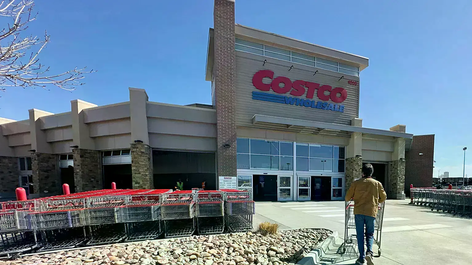Un cliente empuja un carrito hacia la entrada de un almacén de Costco en Sheridan, Colorado.
