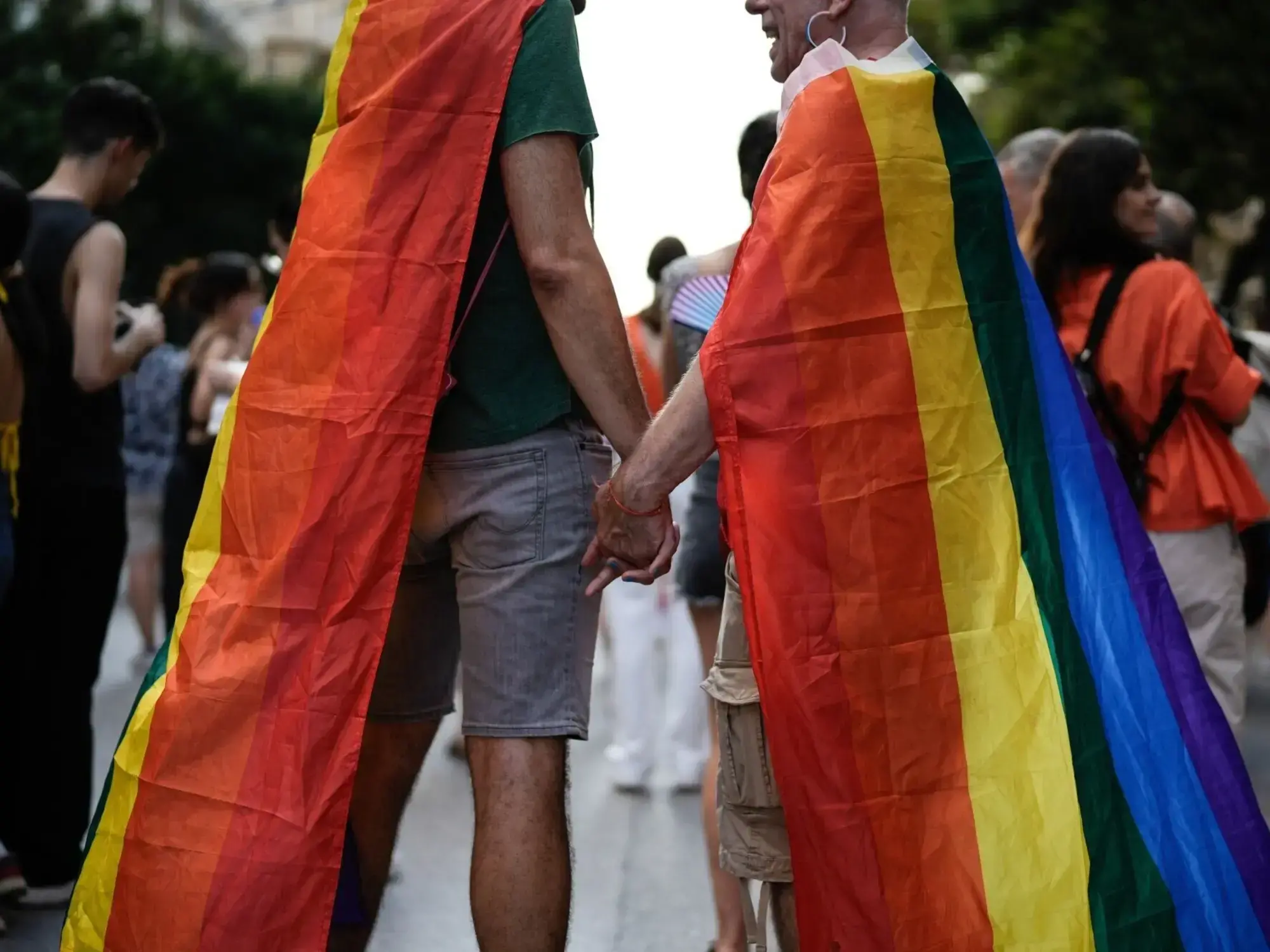 Dos personas caminan de la mano en una marcha del Orgullo en Grecia.