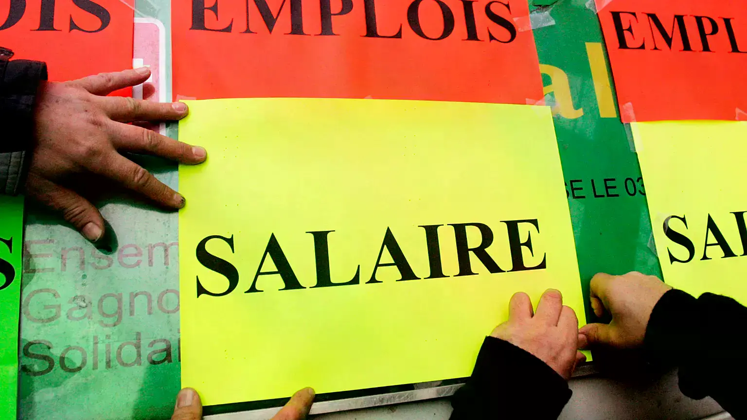 Funcionarios pegan carteles con las palabras «Empleo» y «Salario» durante una protesta salarial en Lille, Francia.