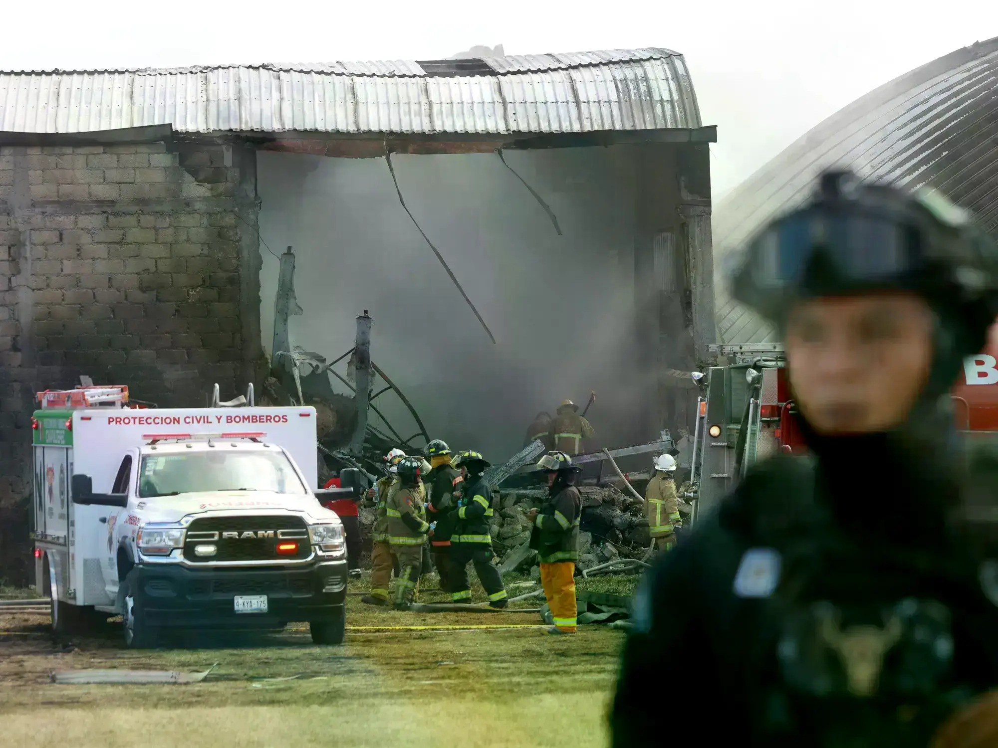 Integrantes de Protección Civil trabajan en la bodega industrial donde cayó la avioneta.