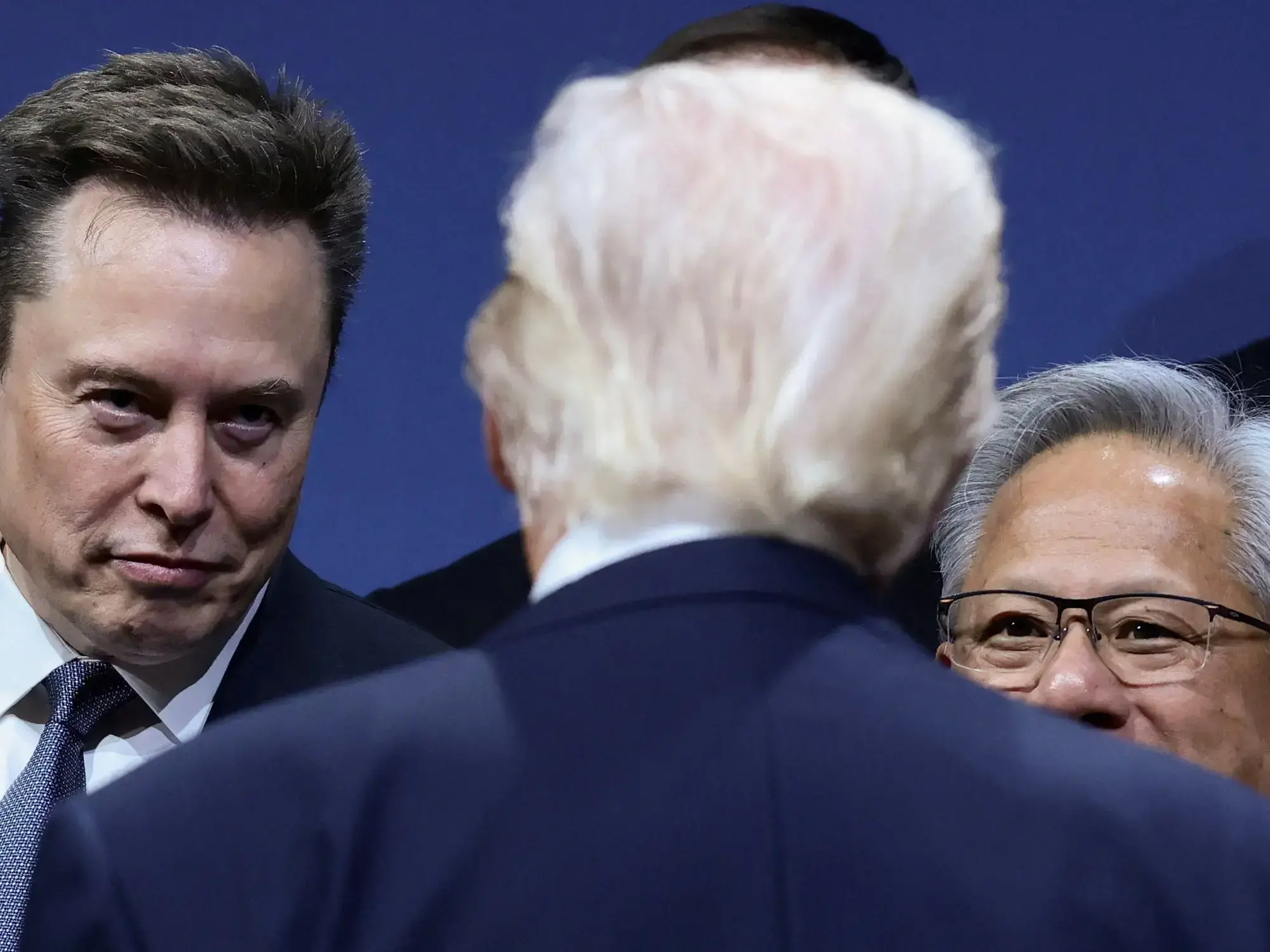 Jensen Huang y Elon Musk observan a Donald Trump durante un foro en Washington.