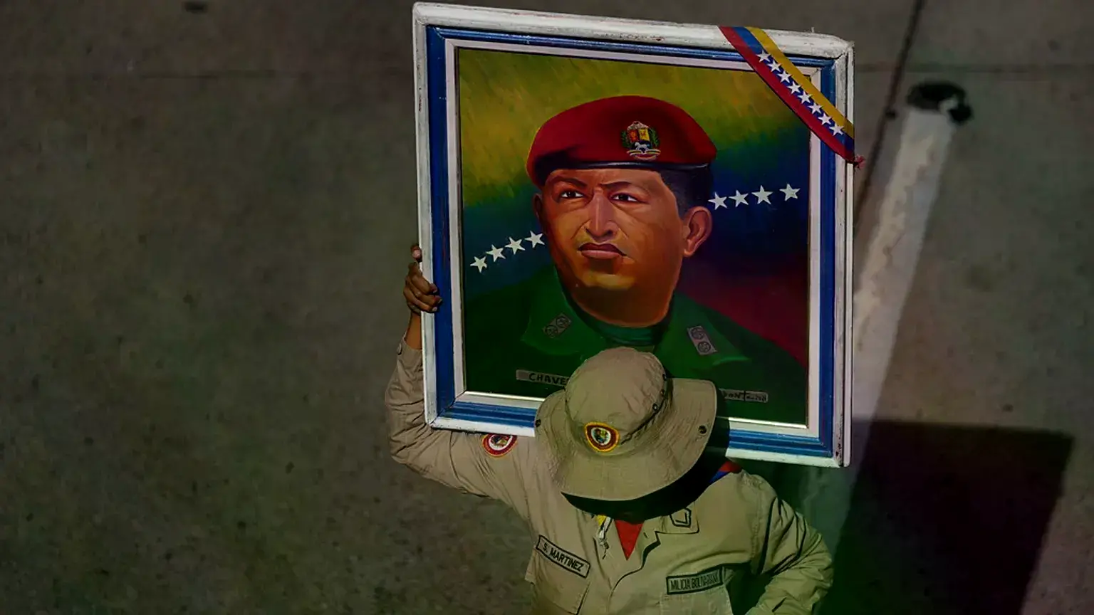 Un miembro de la Milicia Bolivariana sostiene un cartel de Hugo Chávez en una concentración en Caracas.