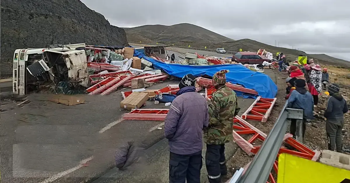 Camión volcado con la carga esparcida en la carretera.