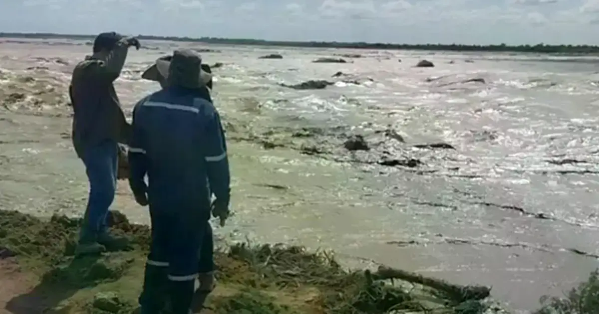 Trabajadores de la gobernación observan la crecida de un río