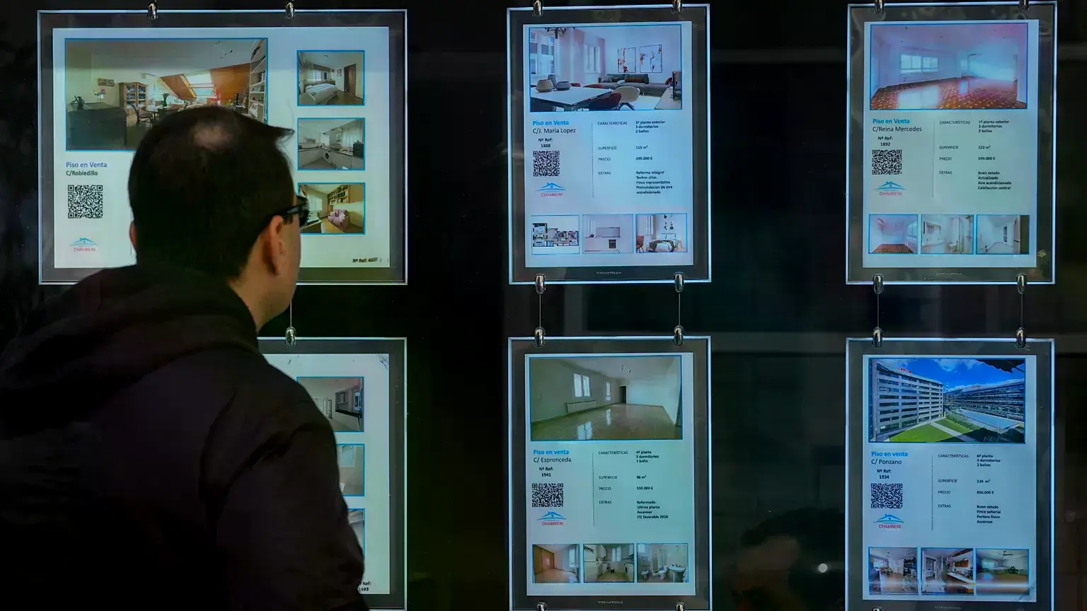 Un hombre visualiza el precio de la vivienda en una inmobiliaria.