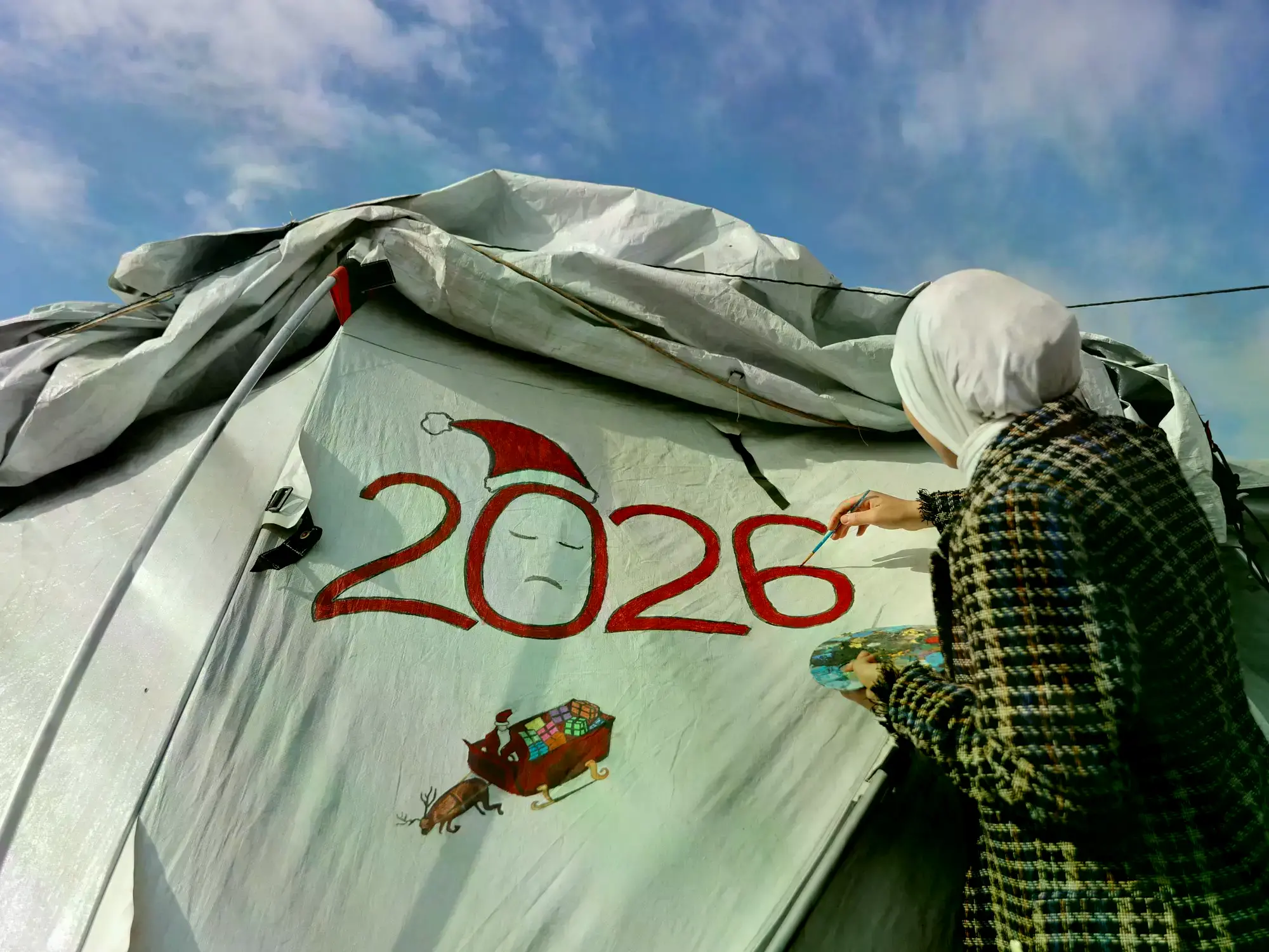 Niños palestinos esperan el año nuevo entre ropa colgada en un campamento de Gaza.