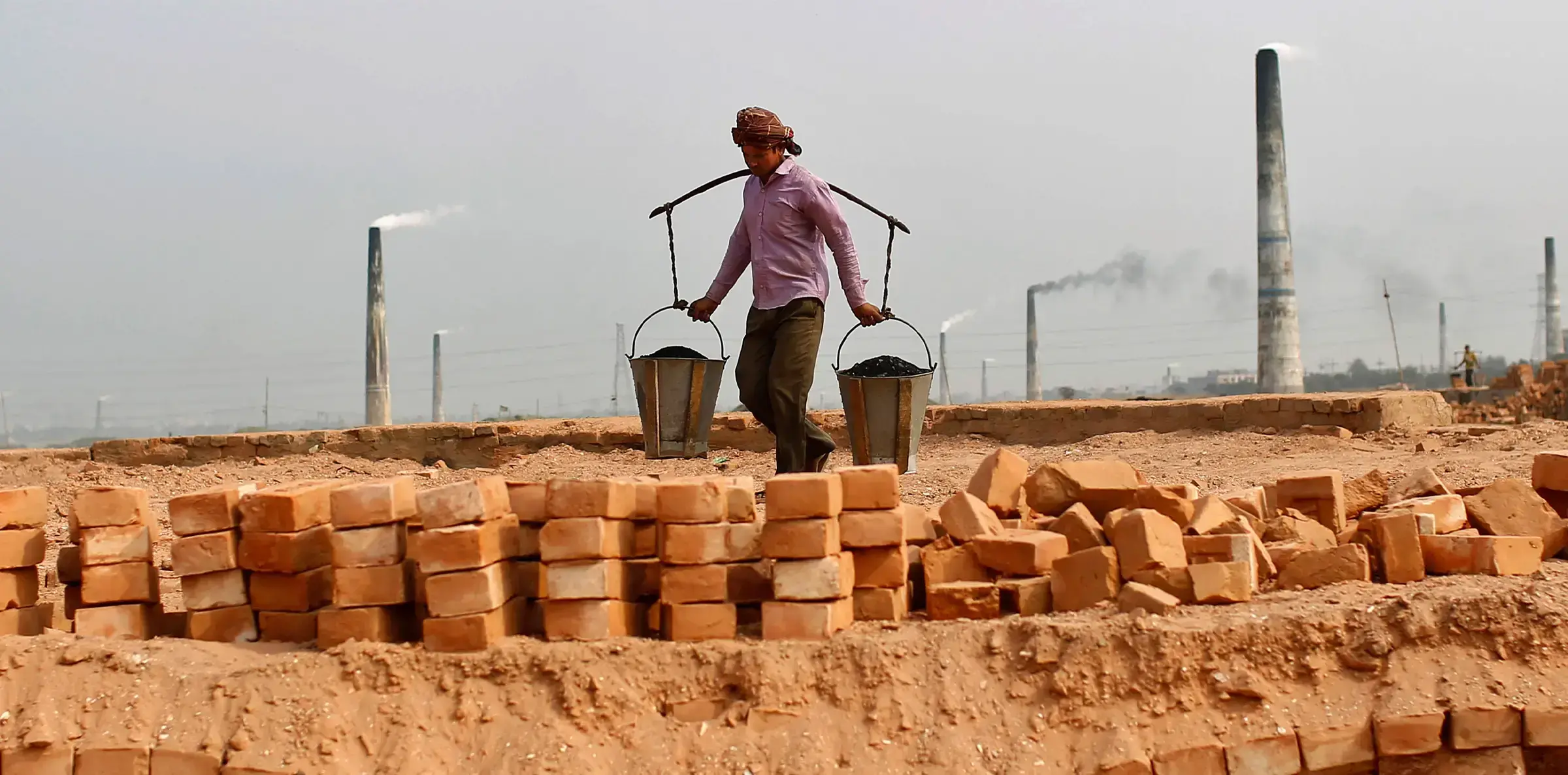 Humo sale de una chimenea mientras trabajadores laboran en un campo de ladrillos en las afueras de Dhaka, 2012.