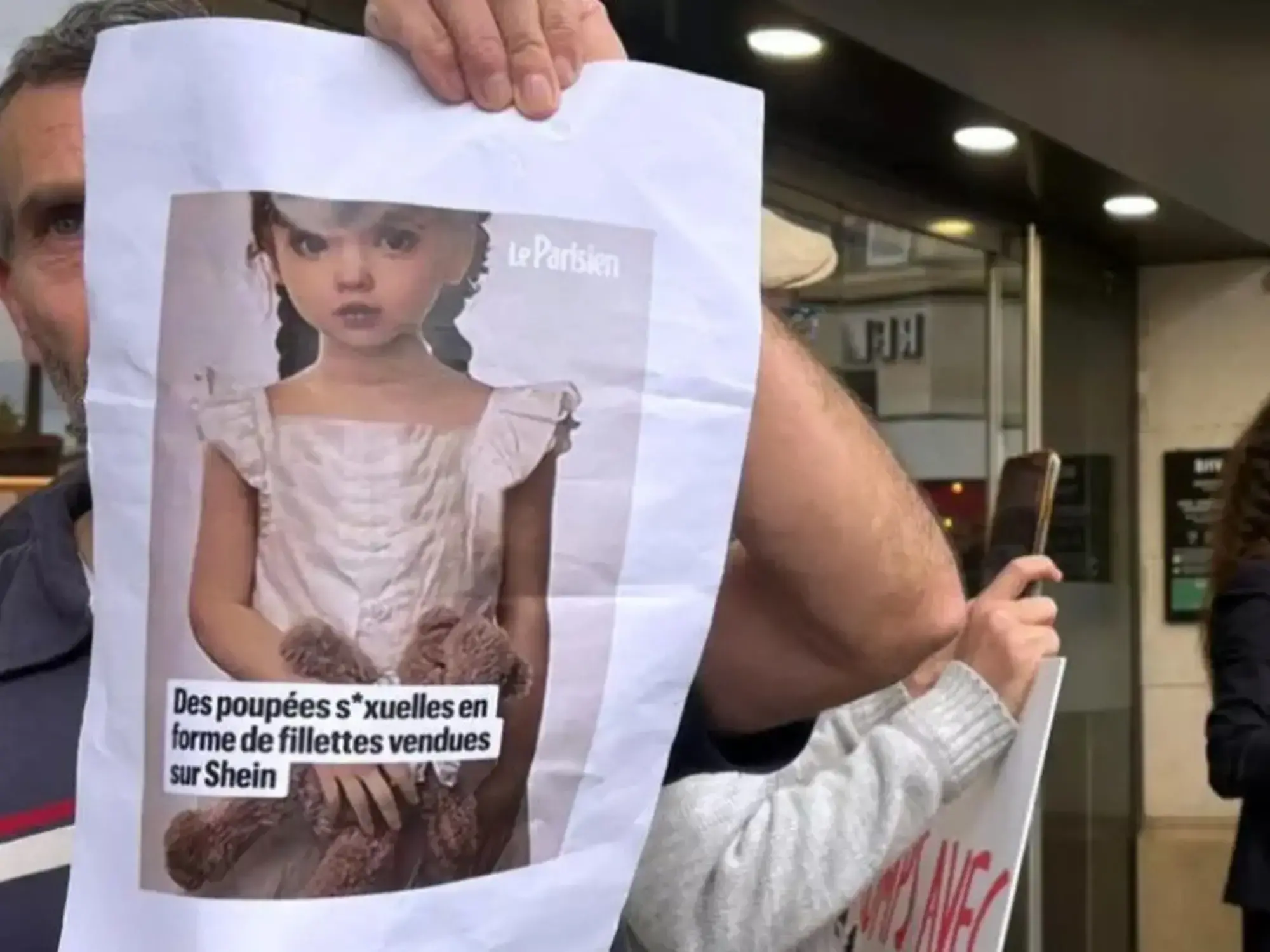 Un manifestante sostiene la foto de una muñeca sexual con apariencia infantil frente a la tienda de Shein en París.