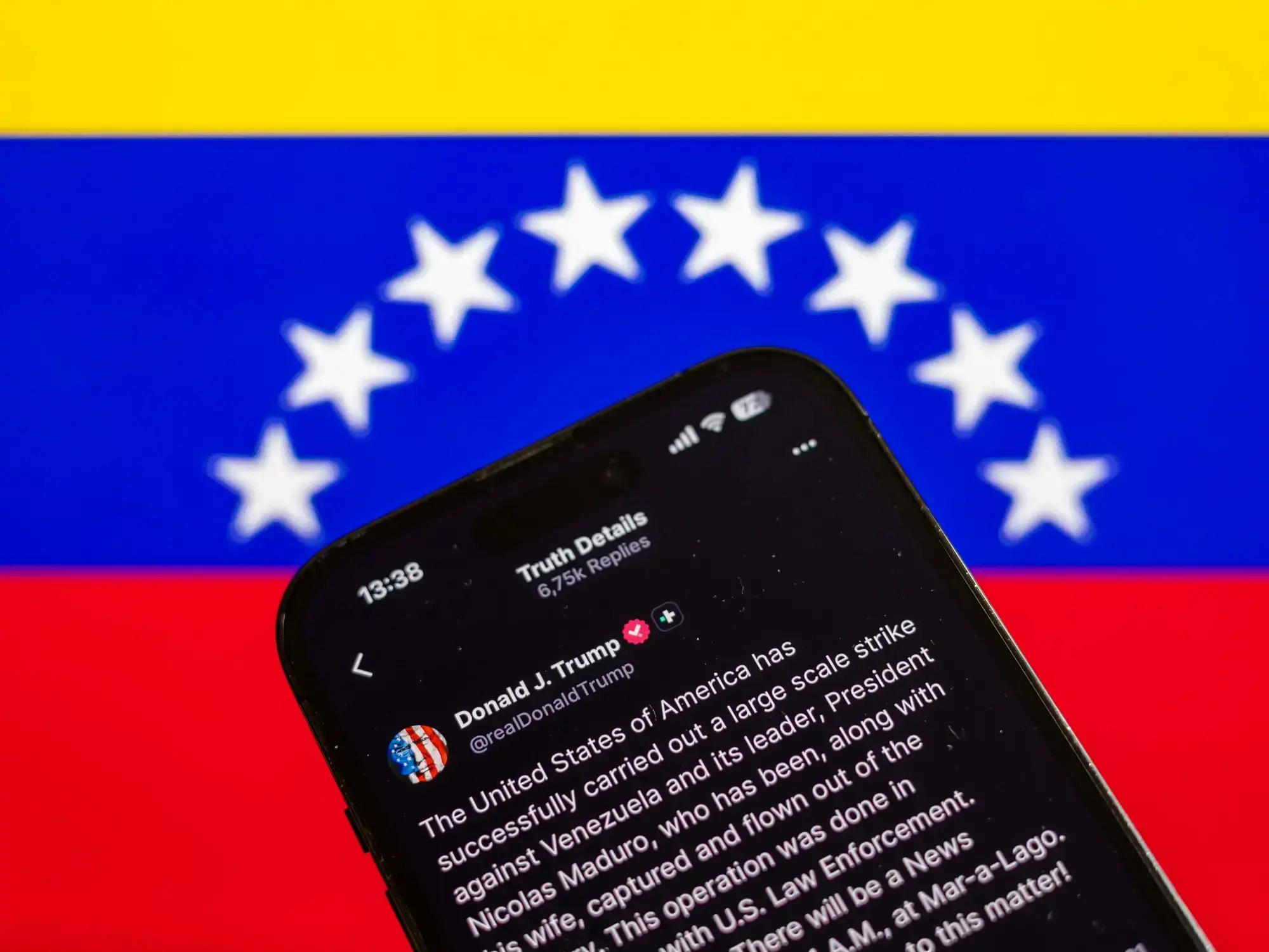 Un teléfono celular con el mensaje de Donald Trump anunciando el ataque contra Venezuela.