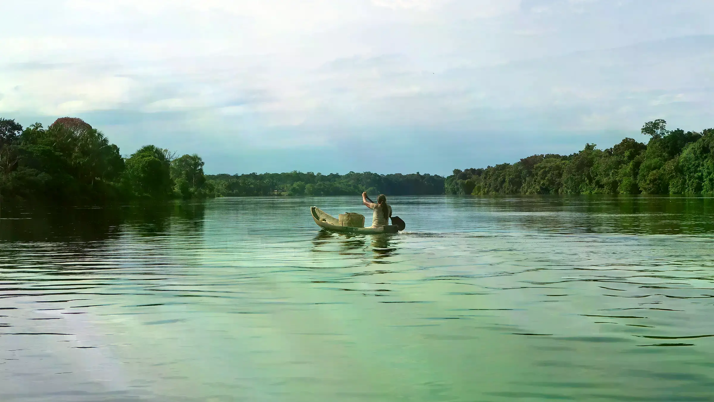Mujer de la comunidad Macaquiño empuja su canoa por el río Vaupés hacia su chagra.