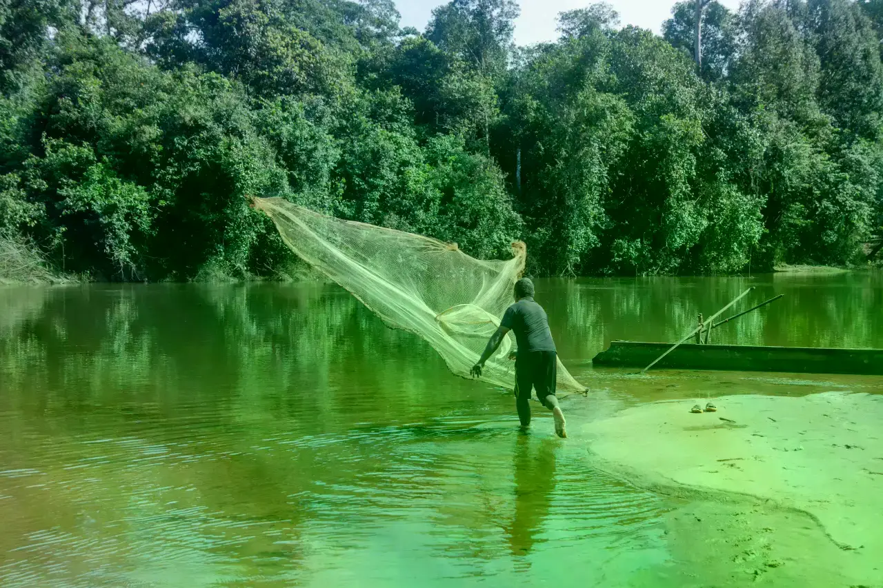 Van Bo pesca en un río después de perder sus tierras agrícolas por el proyecto REDD+.