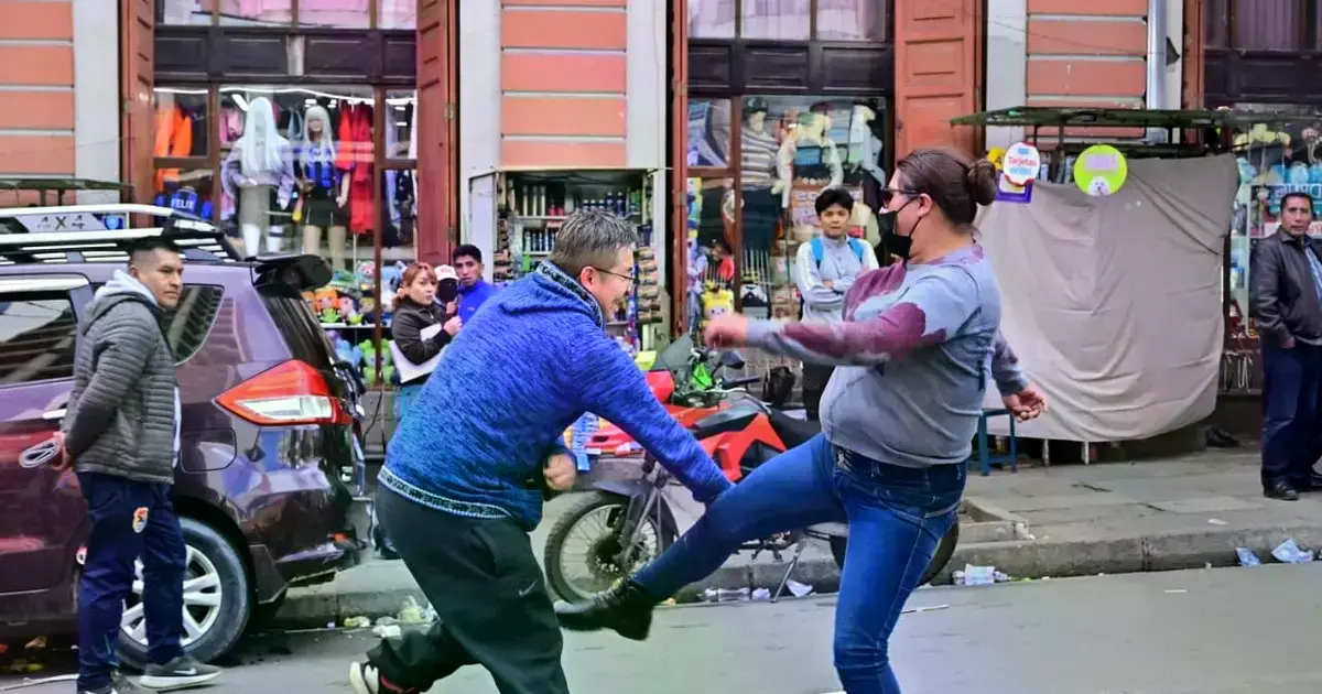 Un ciudadano intenta esquivar una patada de una manifestante durante las protestas.