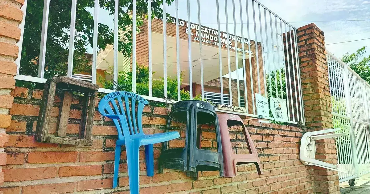 Padres de familia han colocado sillas en la fila en el módulo educativo El Mundo, en la Pampa de la Isla.