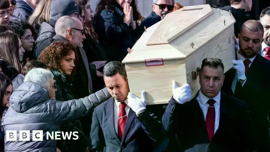 La madre de una víctima toca el ataúd de su hijo en el funeral.