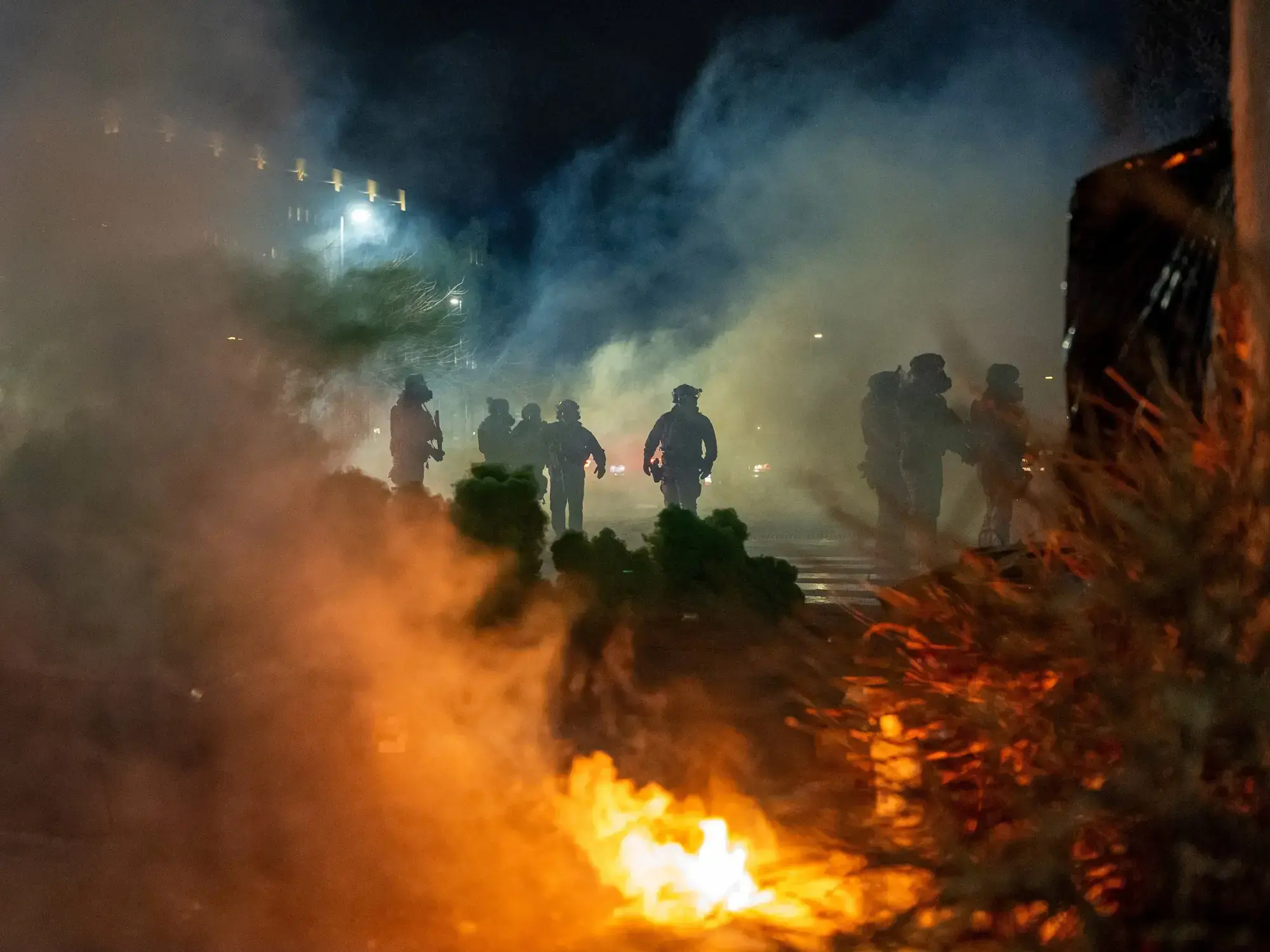 Un manifestante agita una bandera de Estados Unidos mientras la policía lanza gases lacrimógenos en Minneapolis.