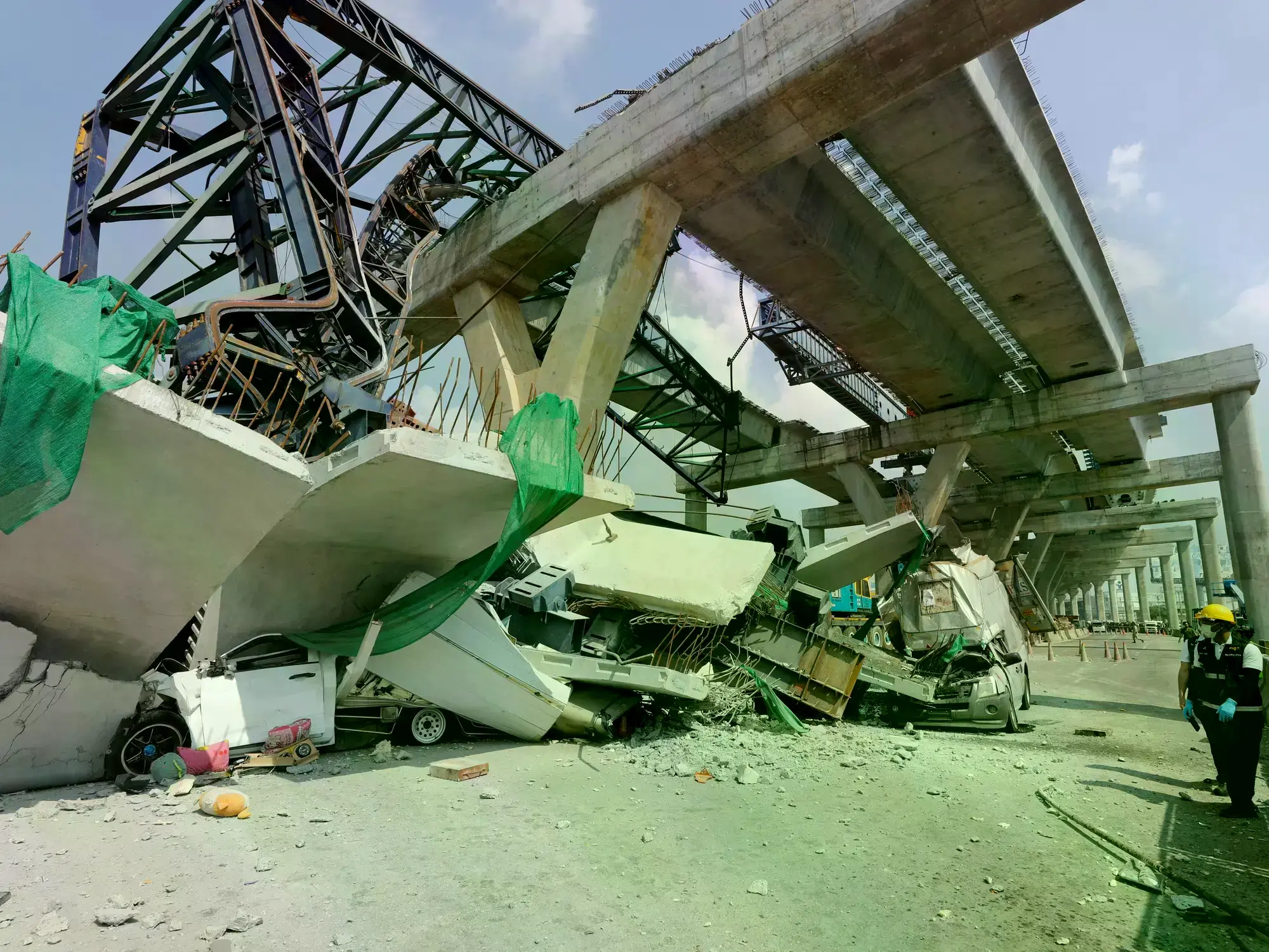 Vehículos aplastados por la grúa y parte del puente que se desplomó.