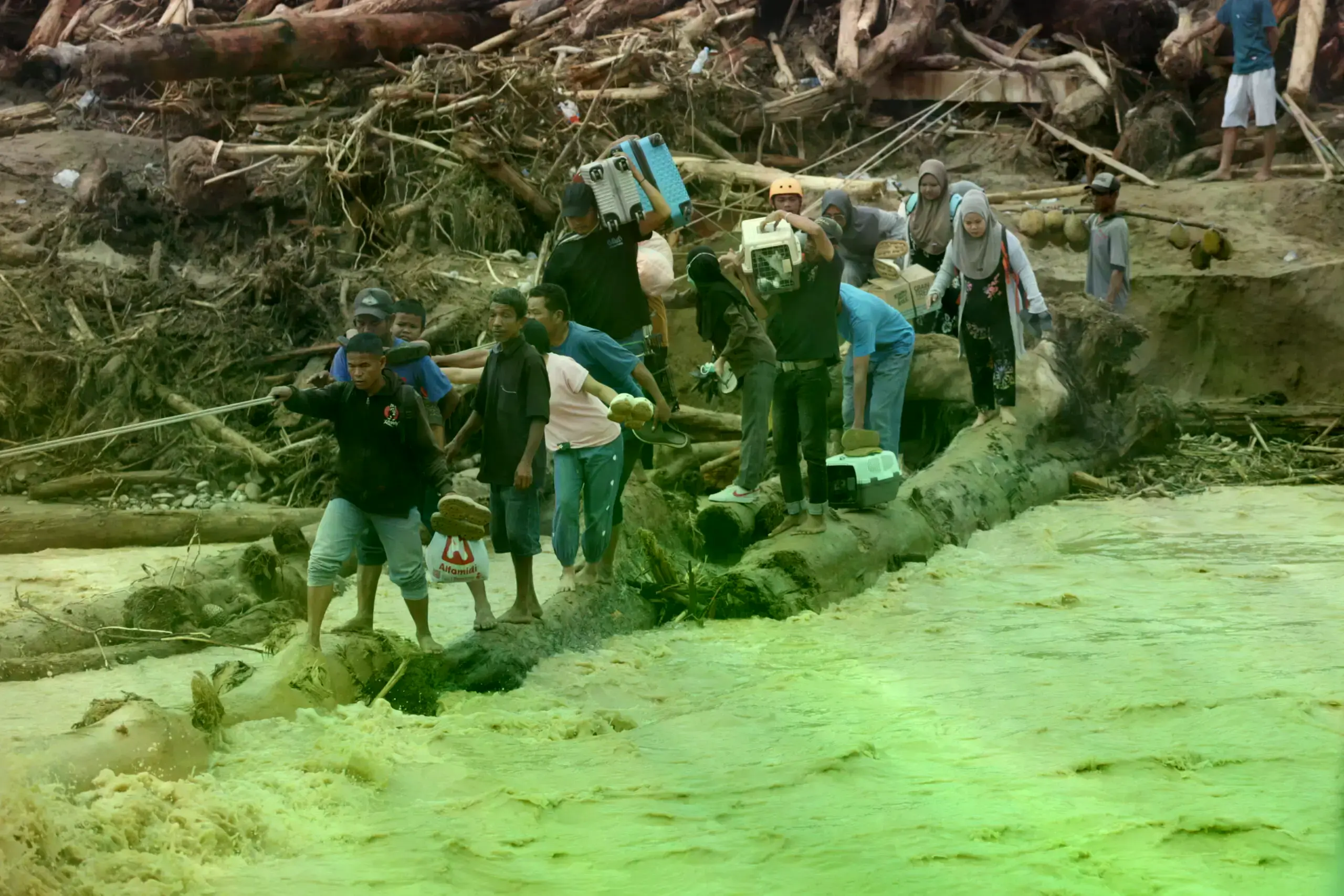 Sobrevivientes de las inundaciones usan troncos para cruzar un río en Batang Toru, Sumatra Norte, el 2 de diciembre de 2025.