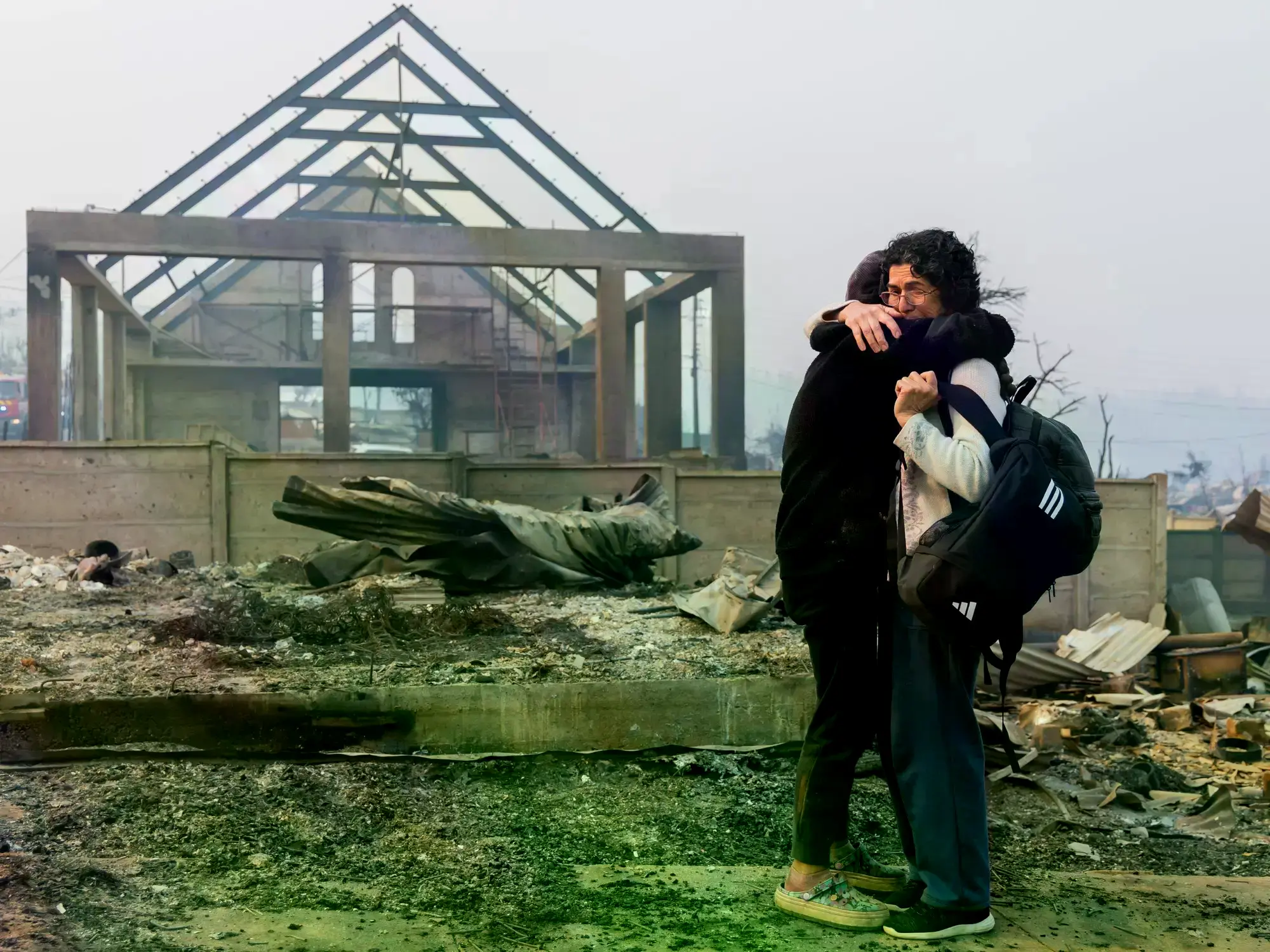 Una mujer abraza a su hija frente a los restos de su casa, en Tomé, Chile.