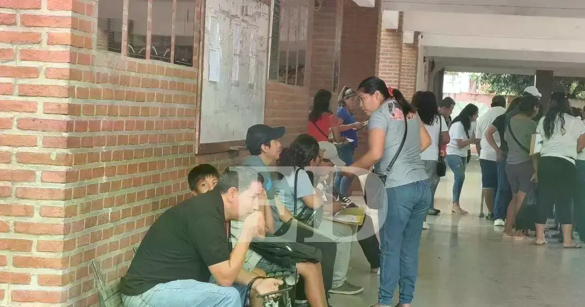 Padres de familia hacen fila en el primer día de inscripciones escolares.