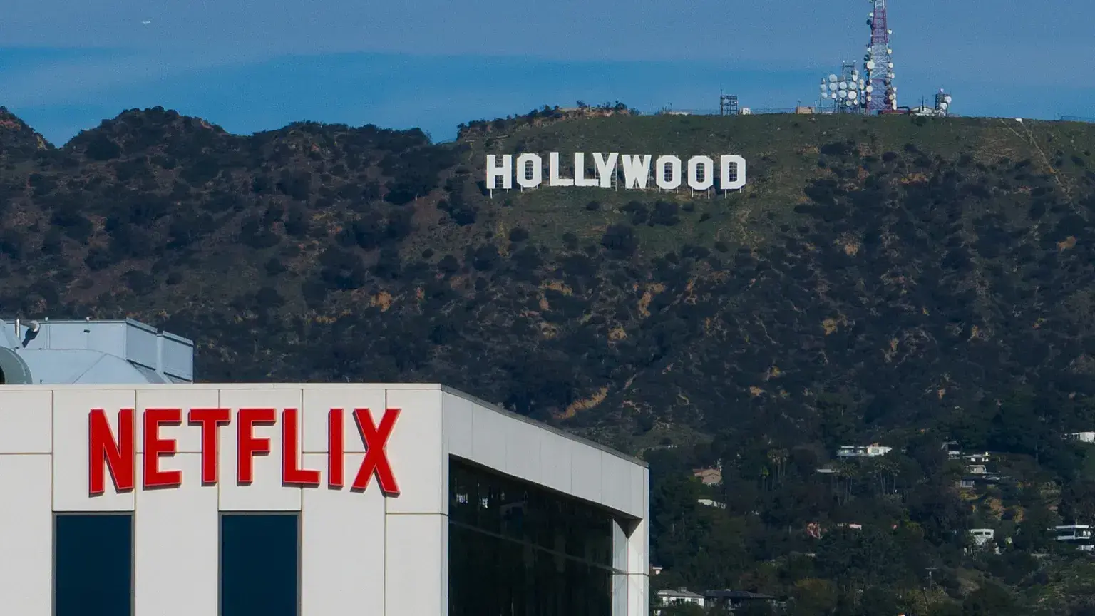 Un cartel de Netflix en lo alto de un edificio en Los Ángeles, con el letrero de Hollywood al fondo.