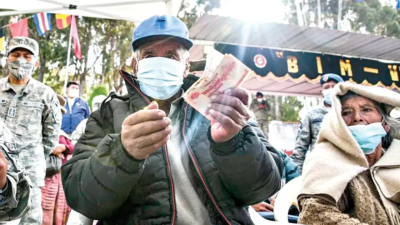 Un beneficiario muestra su dinero tras haber cobrado en una entidad bancaria.