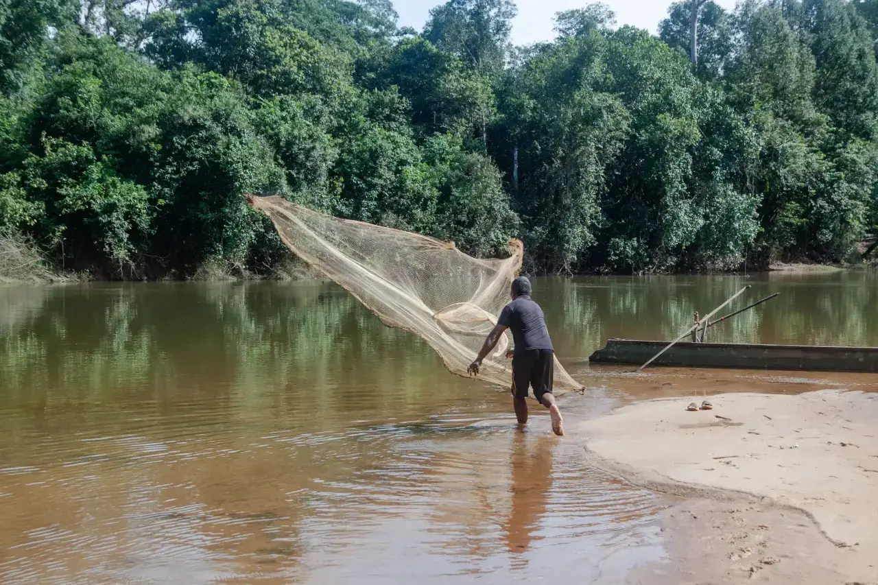 Van Bo pesca en un río tras perder sus tierras de cultivo por el proyecto REDD+.